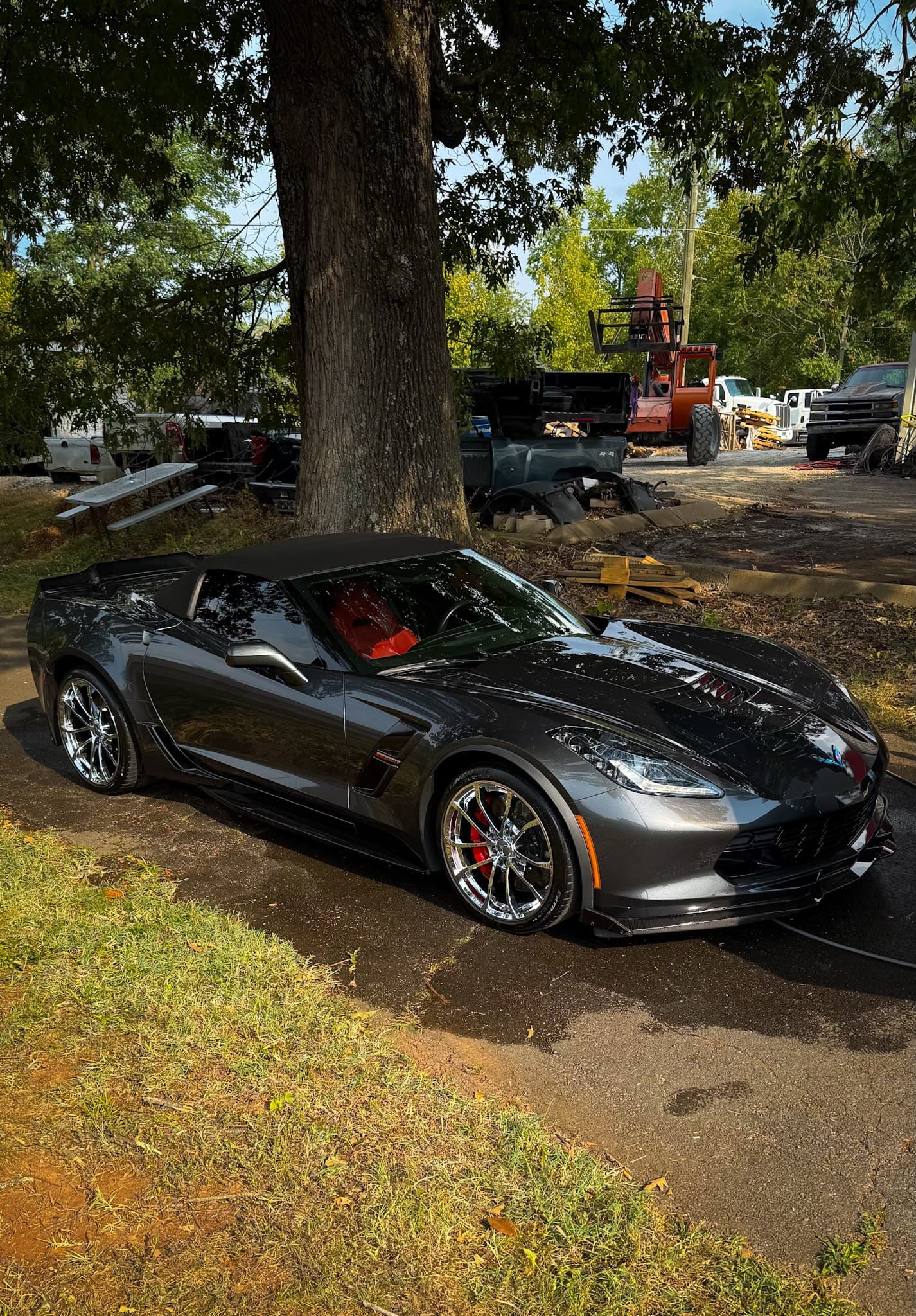 A dark Corvette convertible detailed in the shade of a customer’s front yard